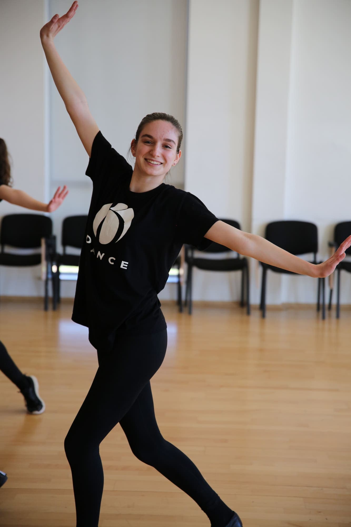 A smiling dancer with her arms stretched wide