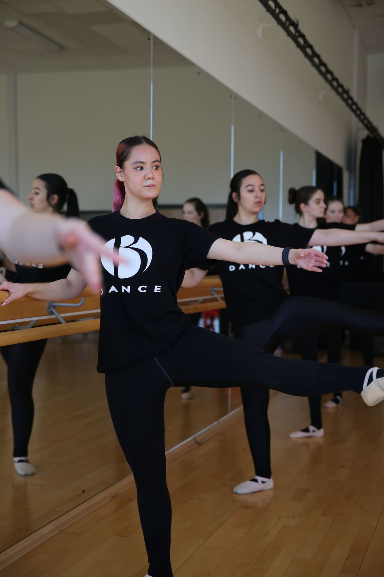 Older dancers working through an extension together at the barre