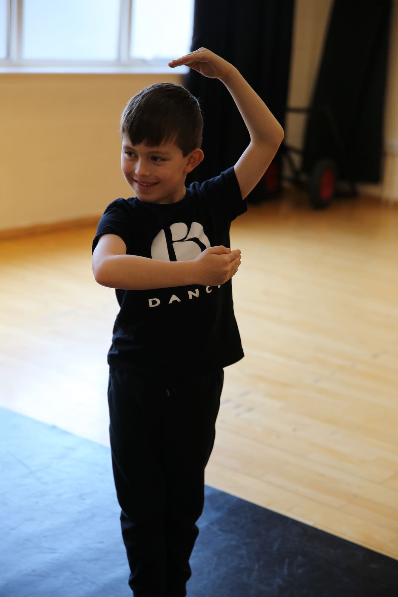 A young dancer smiling as he holds a pose