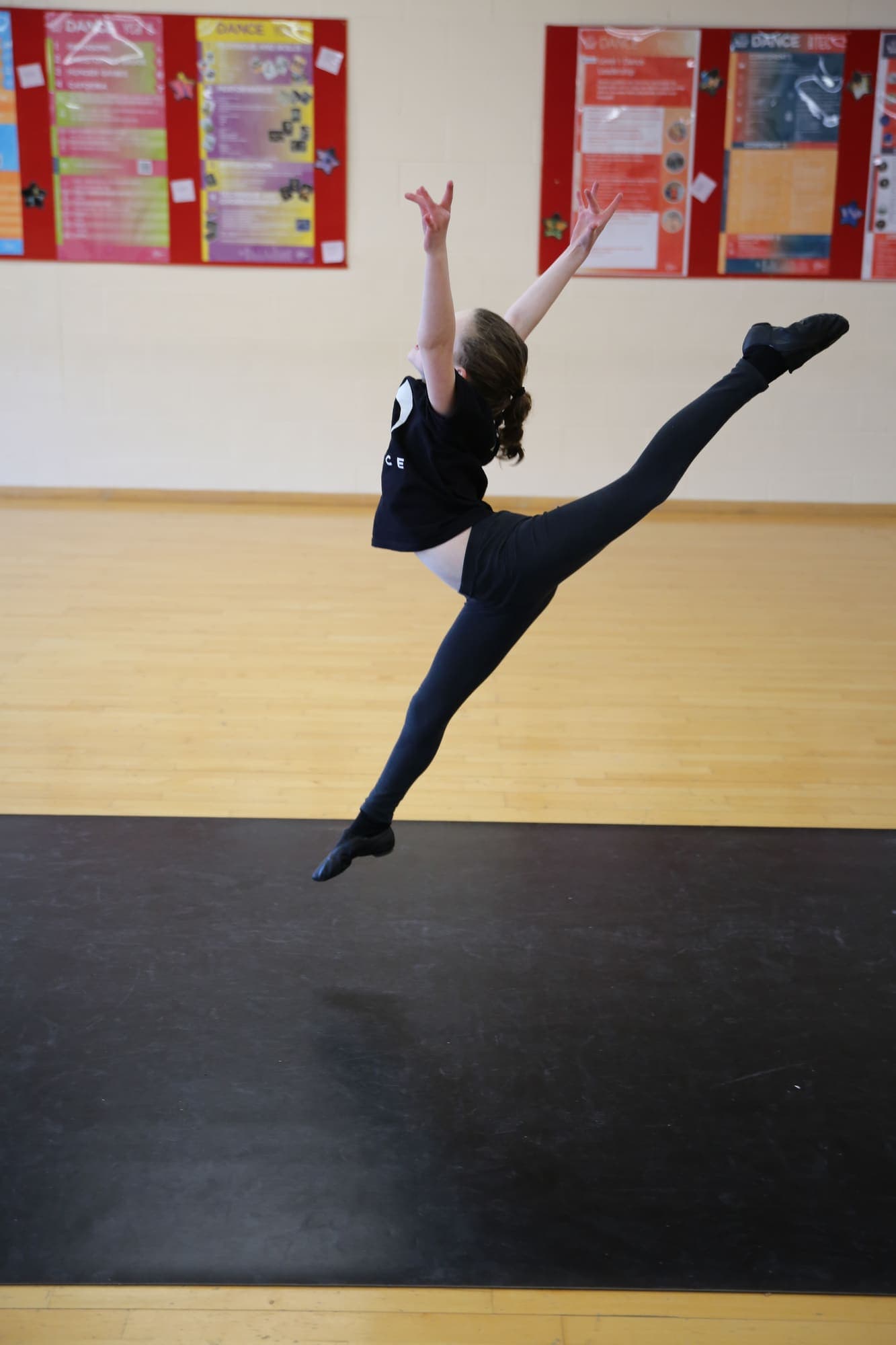 A dancer mid split leap across the studio floor